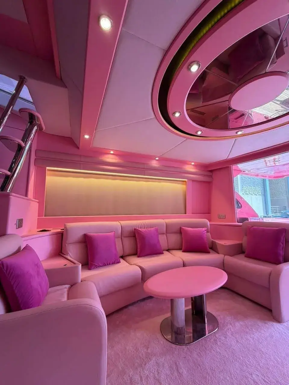 Pink main salon with a wraparound sofa, pink cushions and a round coffee table