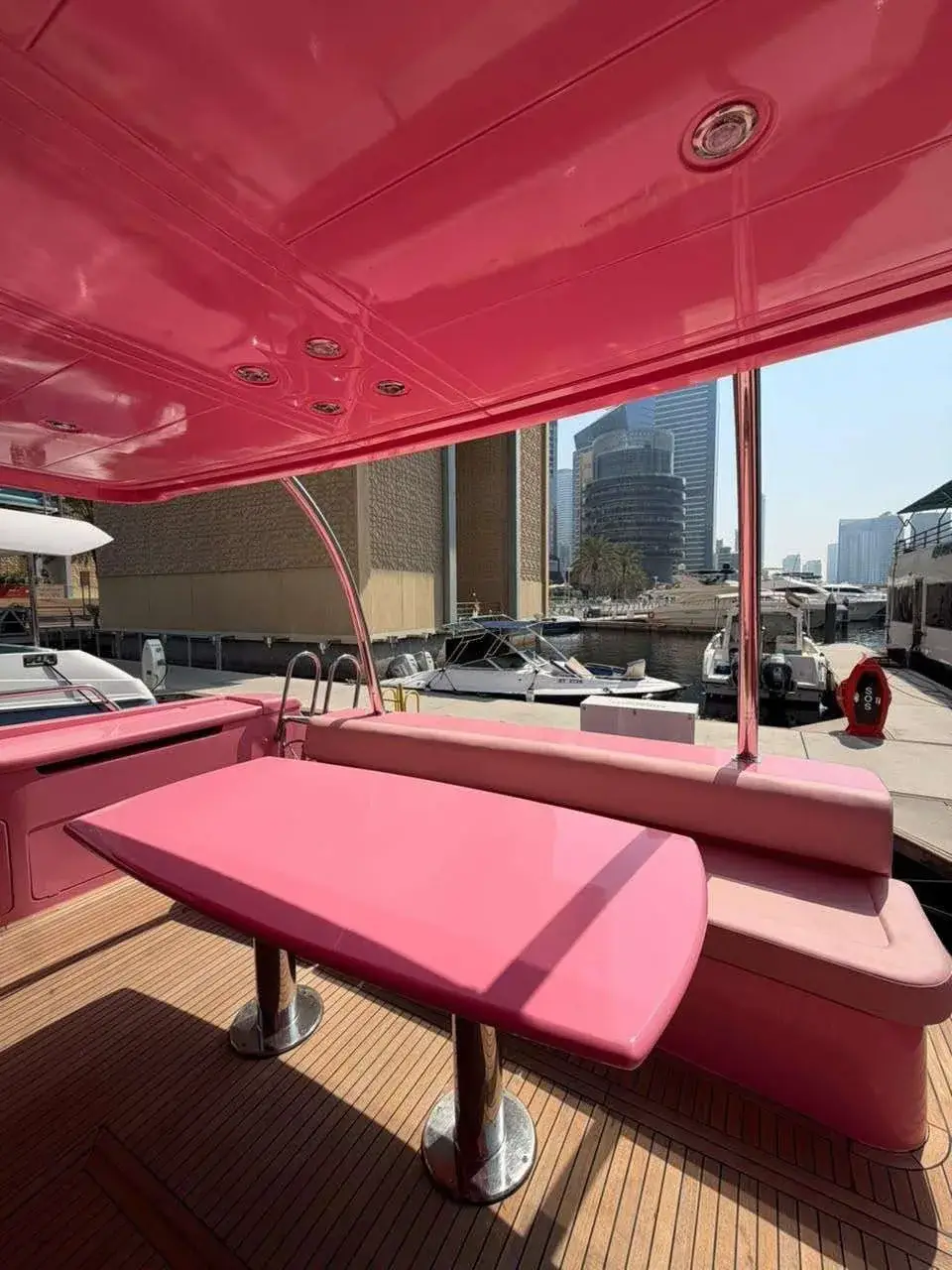 Shaded aft deck lounge with a pink dining table on the Pink Yacht